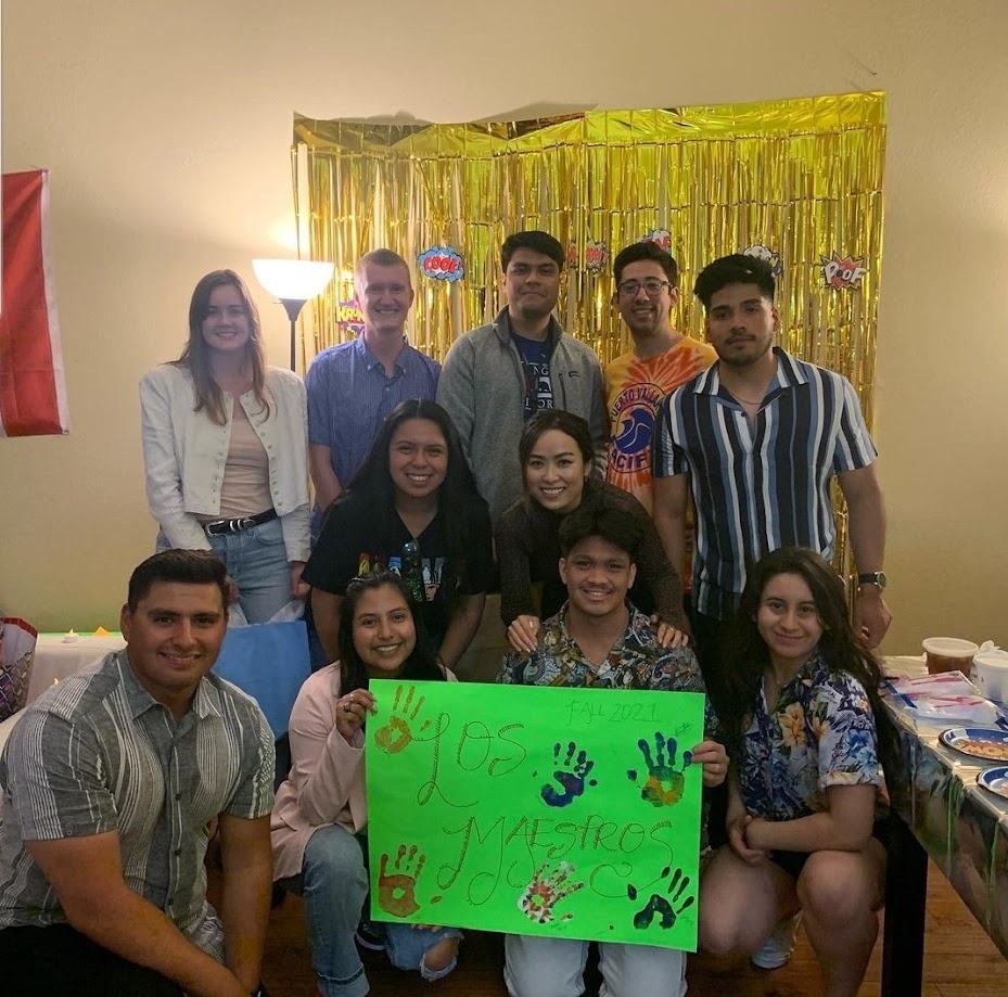 Los Maestros group photo, Fall 2021, students gathered with a handprint poster