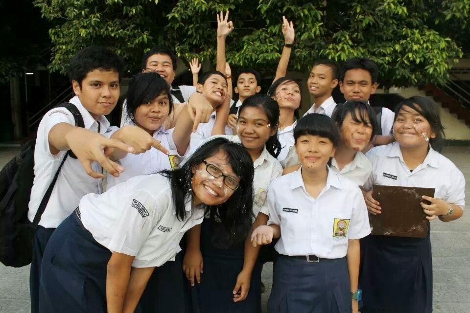 Classmates in school uniform with cake frosting on their faces after a birthday celebration in the schoolyard