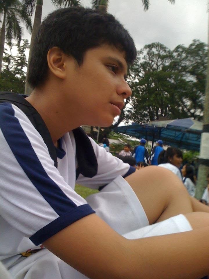 Sitting on the field in the school sports kit, watching whatever is going on