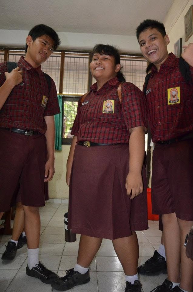 Standing with two classmates in the red plaid school uniform