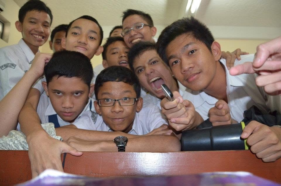 The boys piled over a desk, one of them pointing a phone at the lens