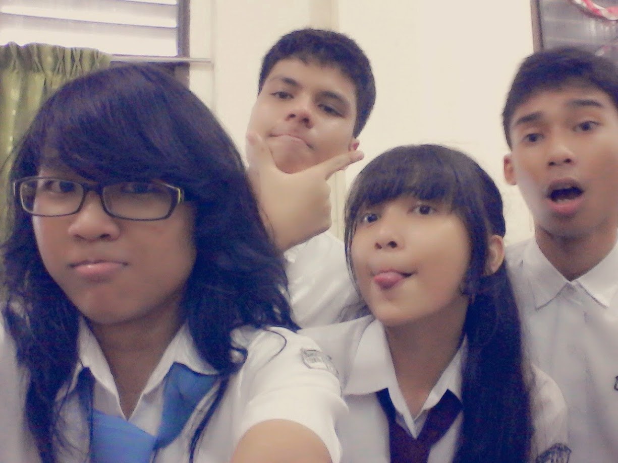Four students in school uniform crowding into a selfie in the classroom
