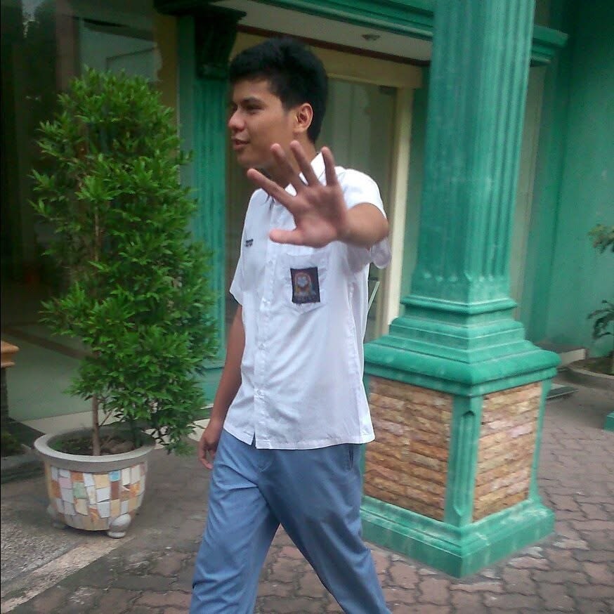 Walking past the green pillars at school in my Indonesian high school uniform, hand up at the camera