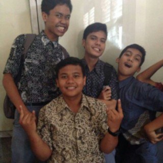 Four friends in batik shirts posing in a school corridor