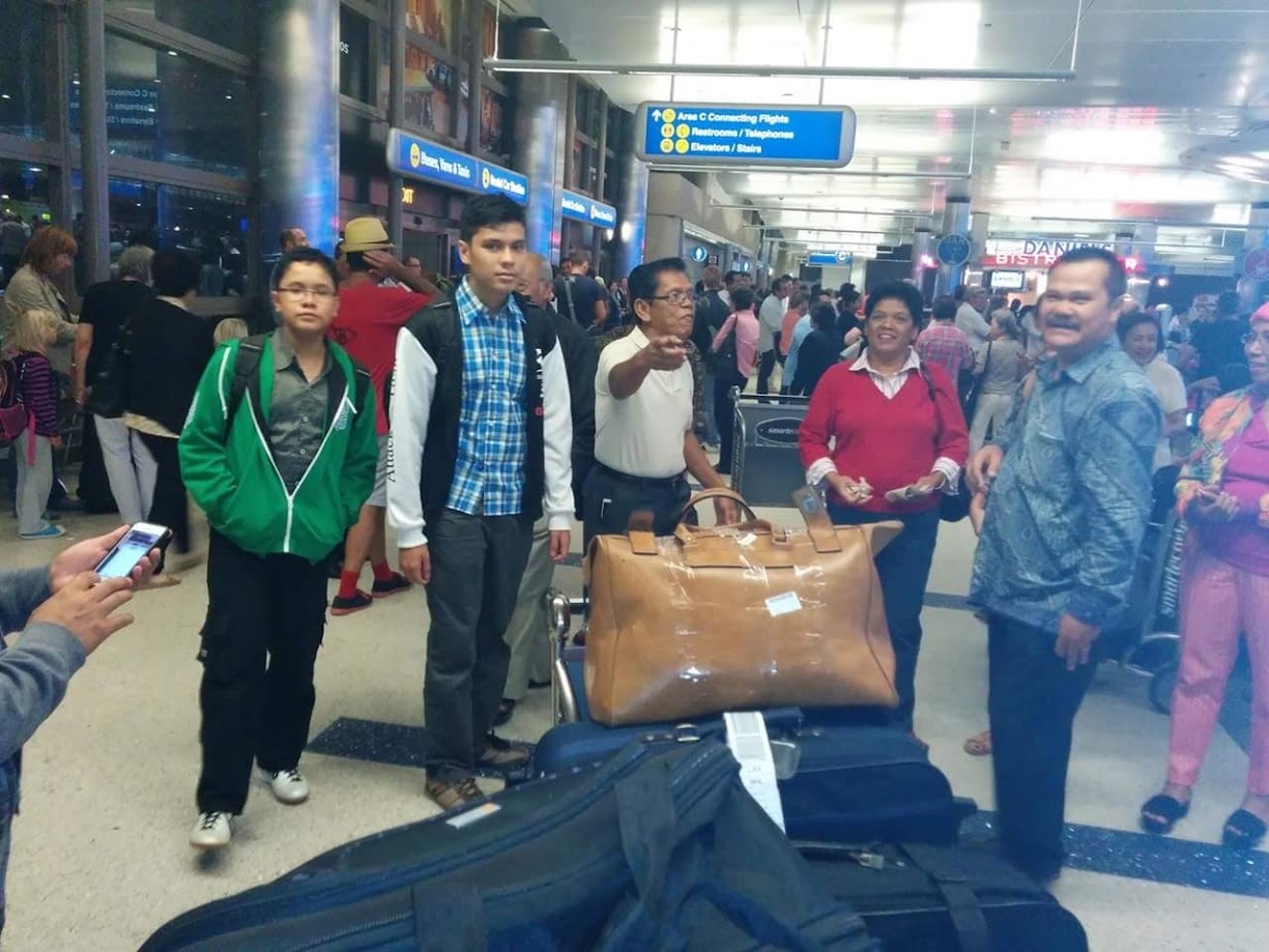 Family standing with luggage in the arrivals hall at LAX