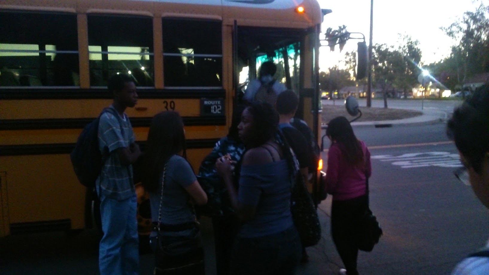 Students boarding a yellow school bus at dusk