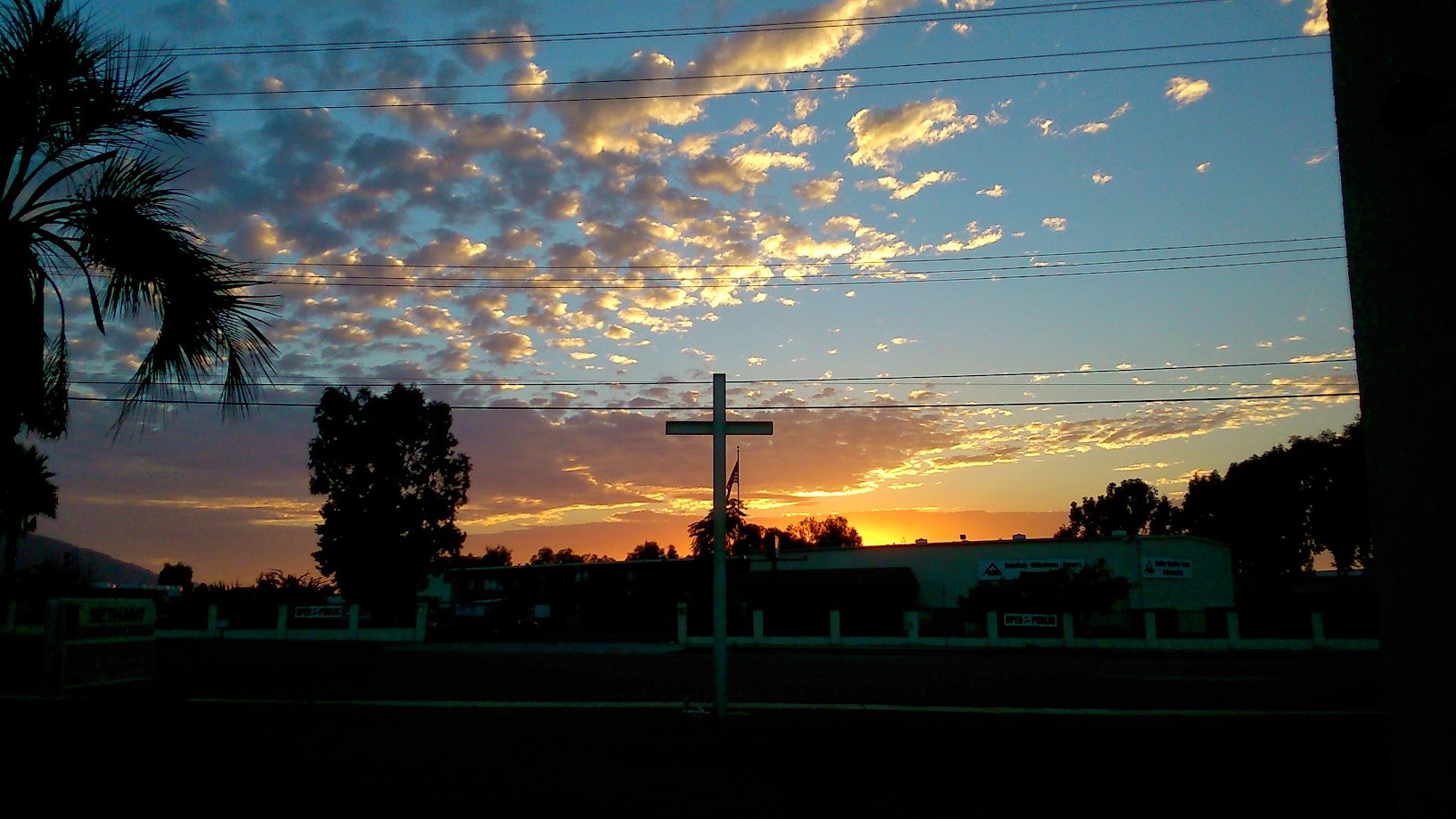 Cross silhouetted against an orange and blue sunset sky