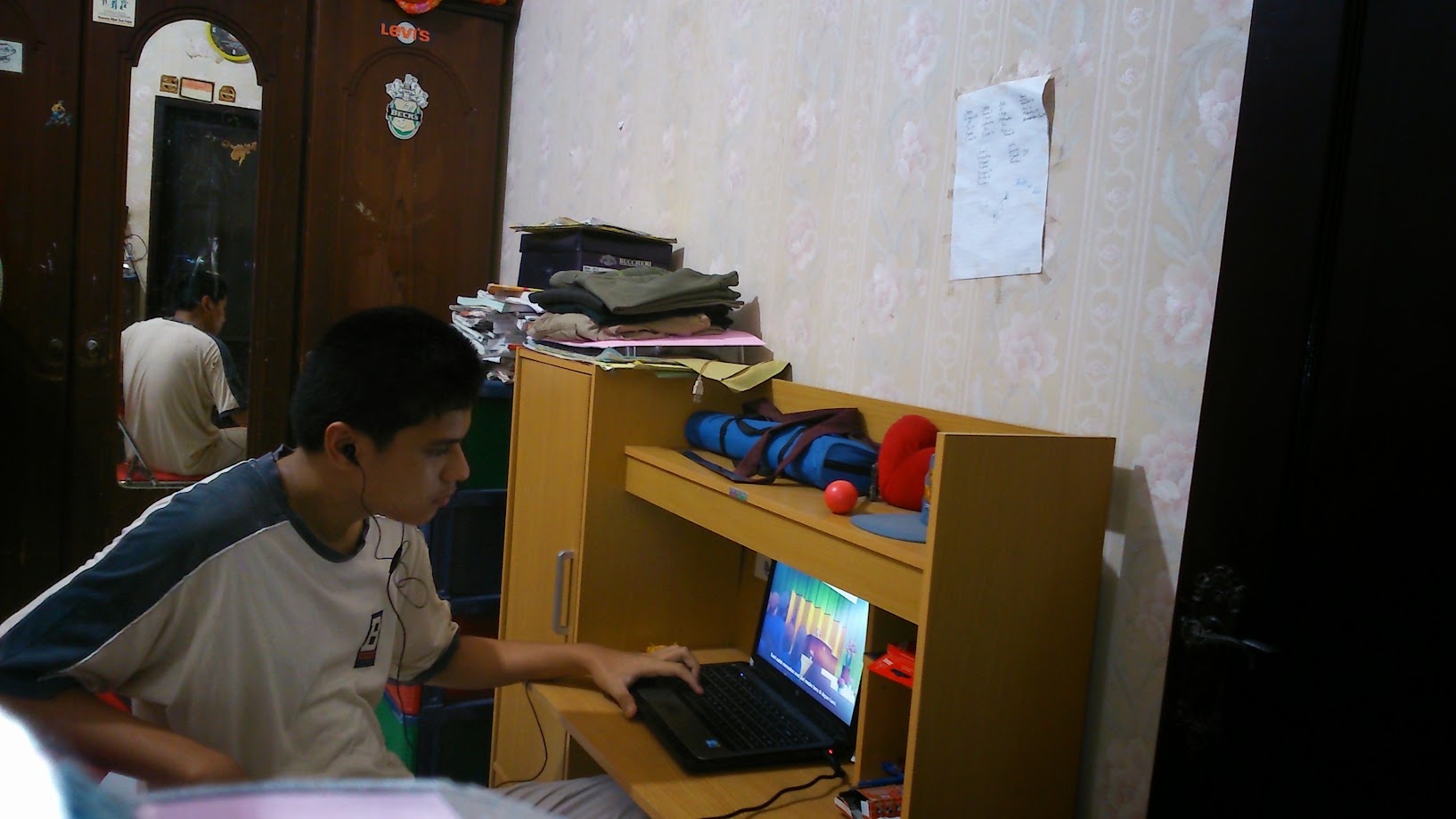 At the laptop with earphones in, in the bedroom at home