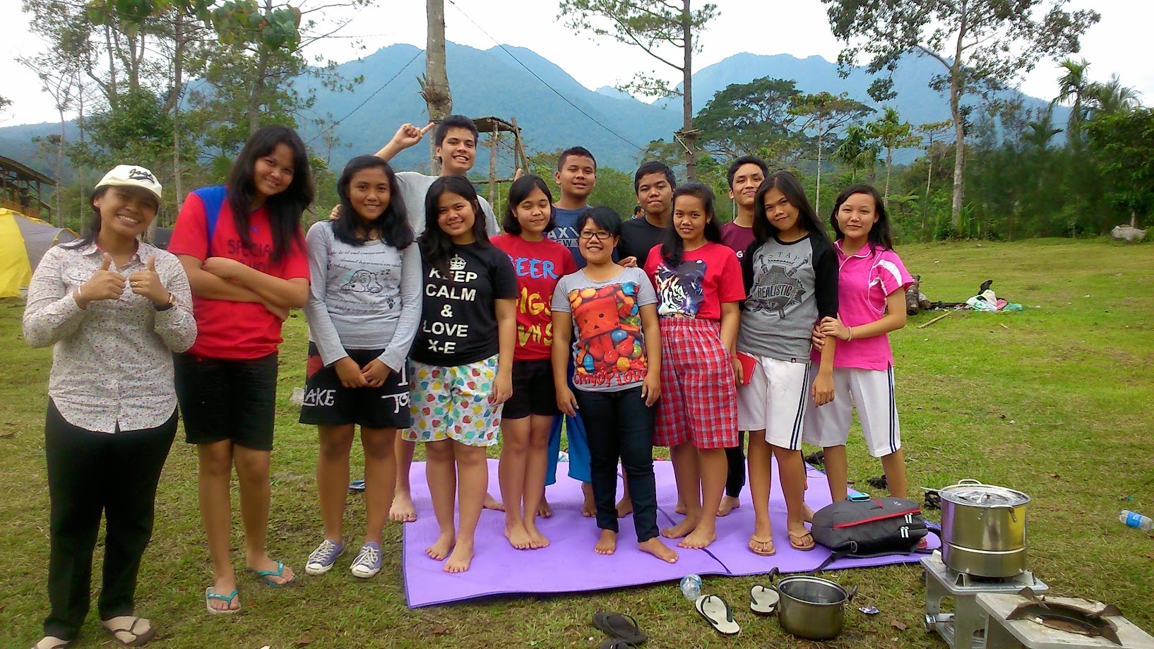 Youth camp group photo on a field with mountains behind