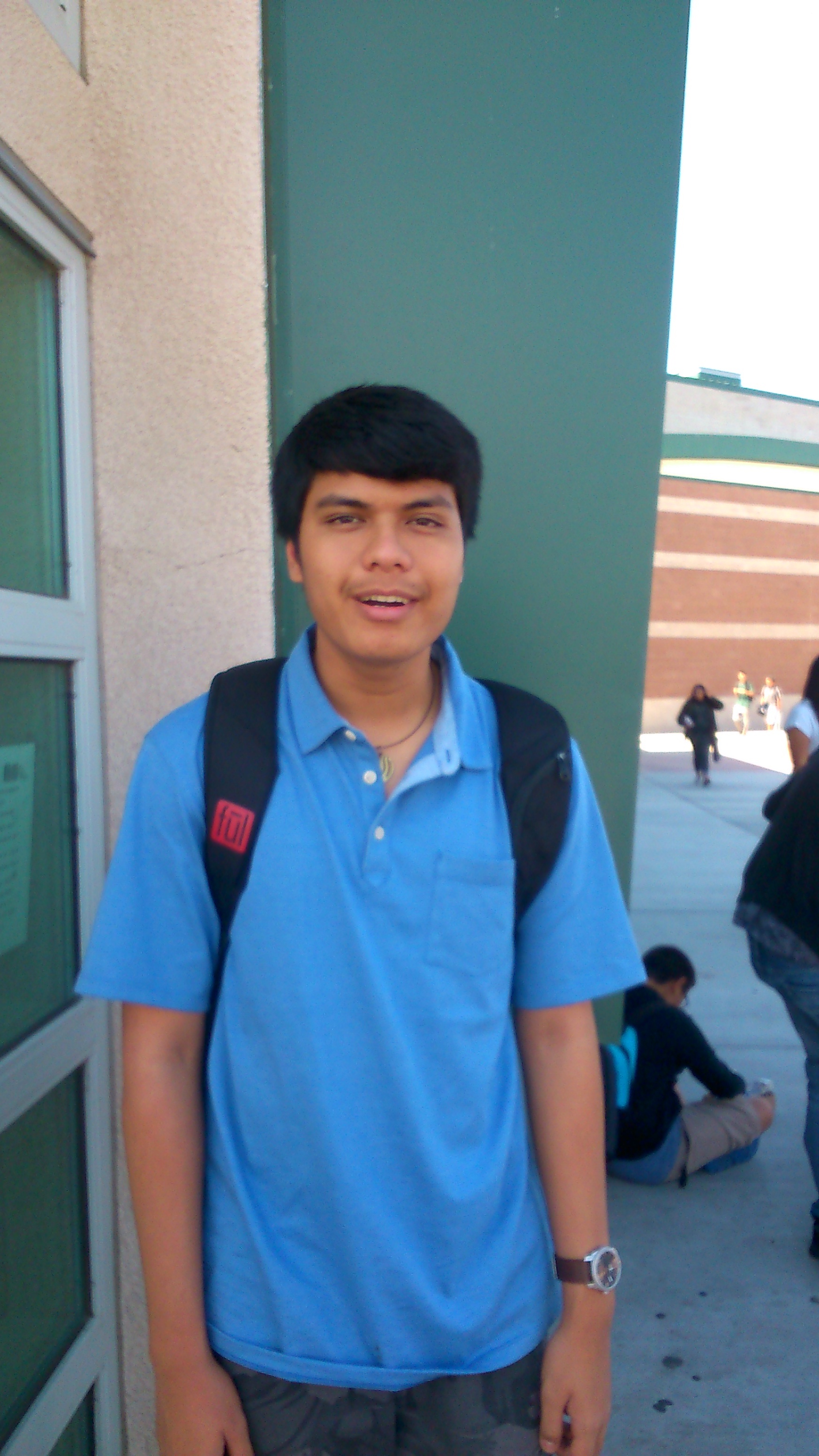 Standing outside a school building in California in a blue polo, backpack on