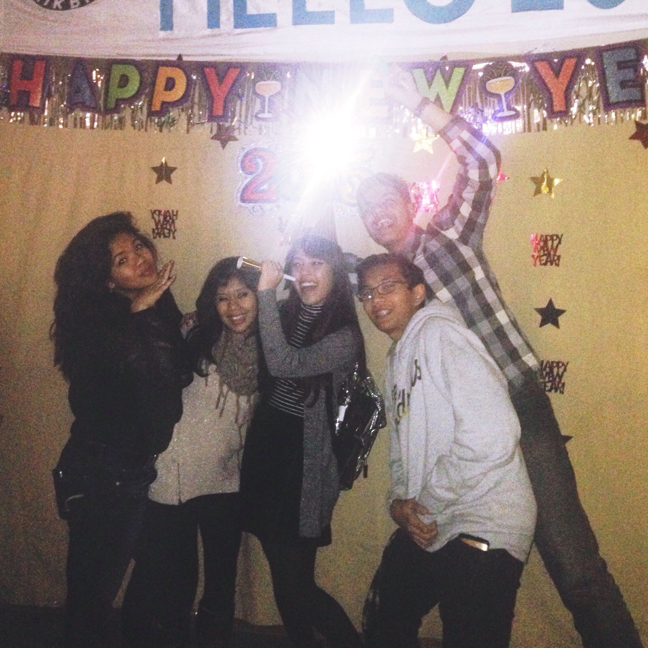 A New Year party with friends, one of us holding a sparkler under a Happy New Year banner