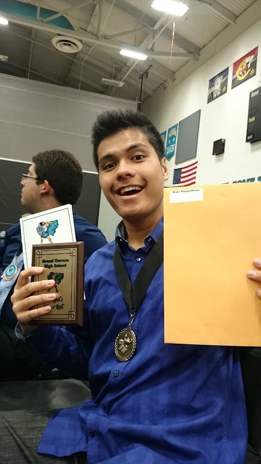 Holding the Principal's Honor Roll plaque and a medal at the awards ceremony