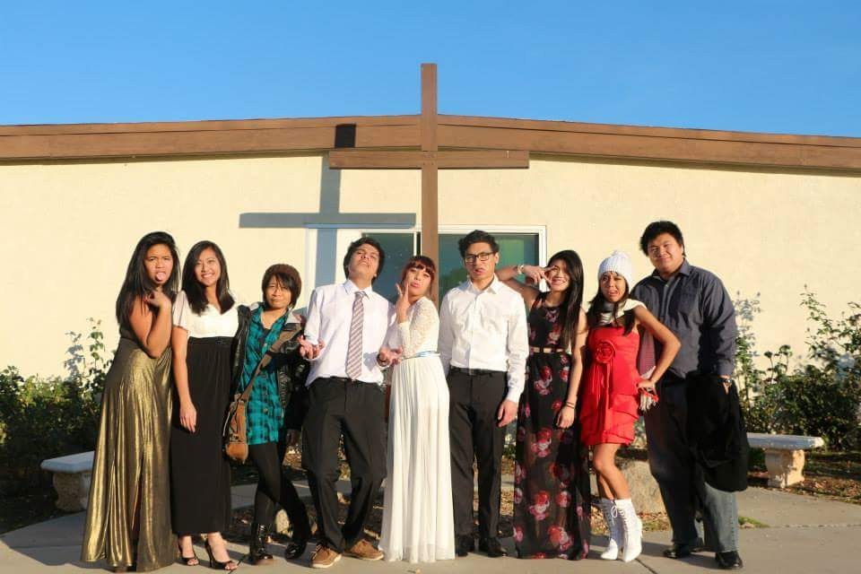 Group in formal wear posing outside the church beneath the cross