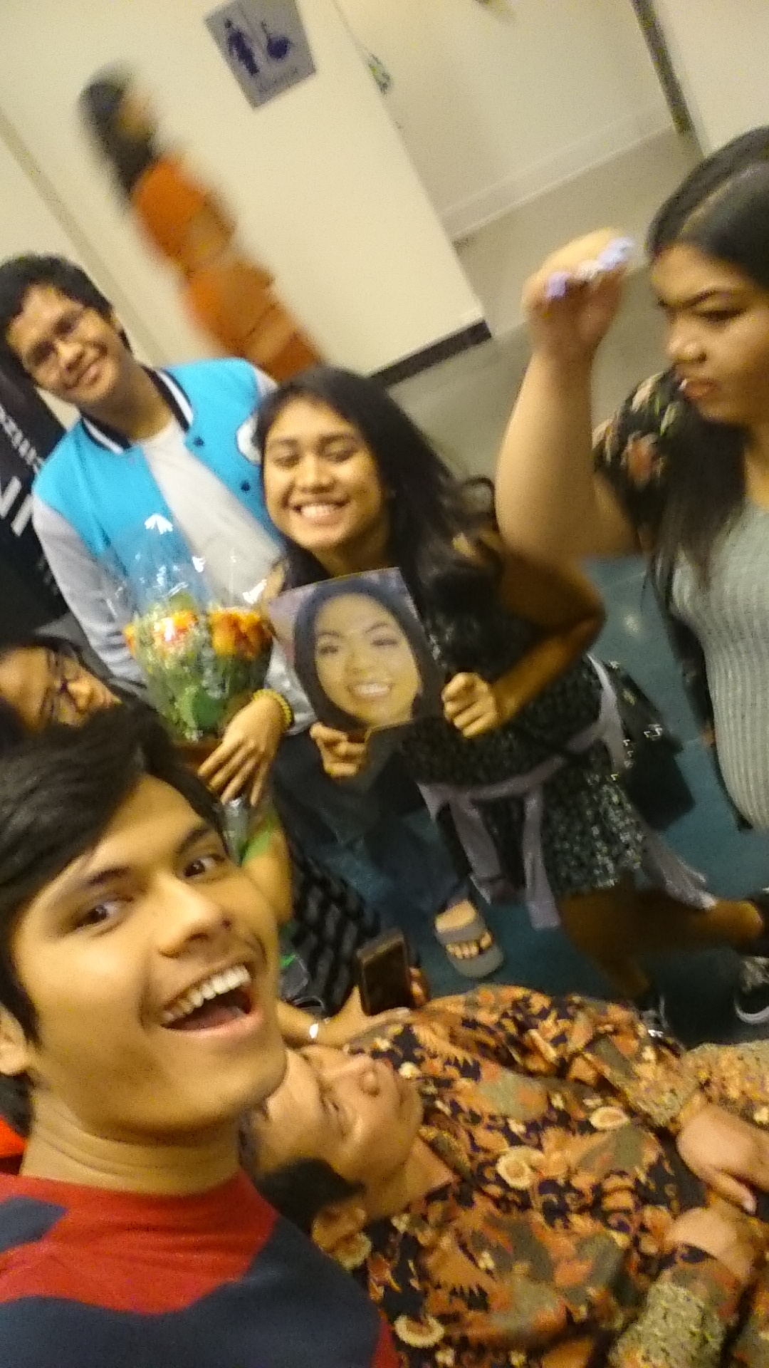 A crowded room of family and friends, flowers in someone's hands
