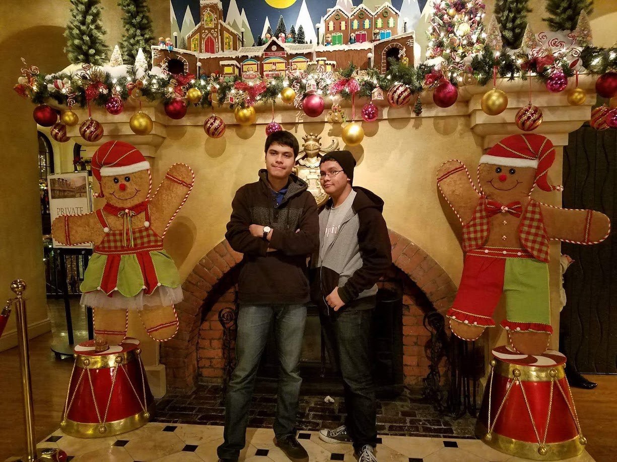 Two of us in front of a Christmas fireplace flanked by giant gingerbread figures