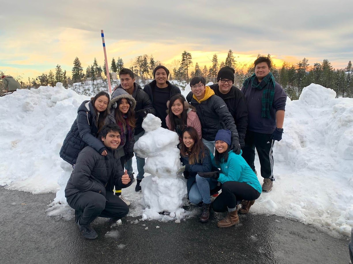 The group posing with a snowman at sunset in the mountains
