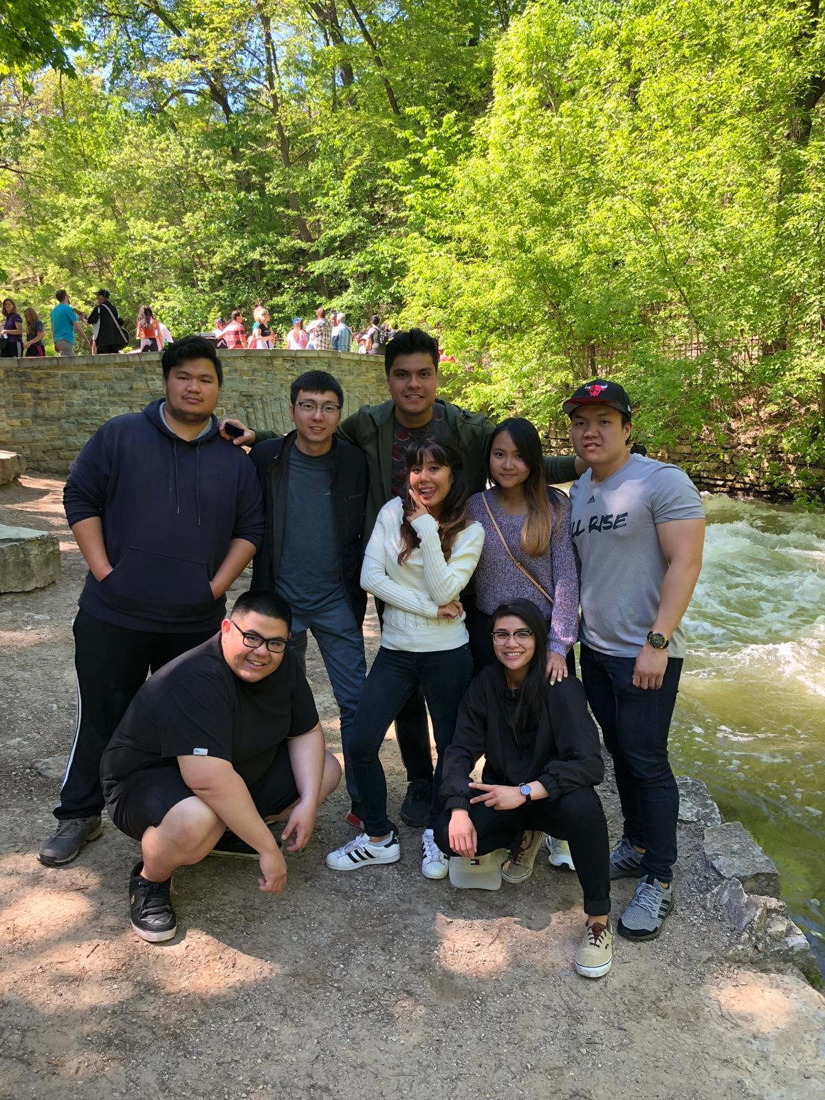 Eight of us posed together on the rocks beside a waterfall in the woods
