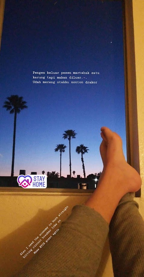 Feet propped on the window at dusk, palm trees outside and a stay home sticker