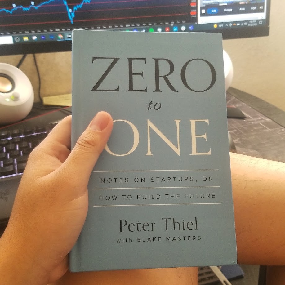 Holding Peter Thiel's Zero to One in front of the trading screens