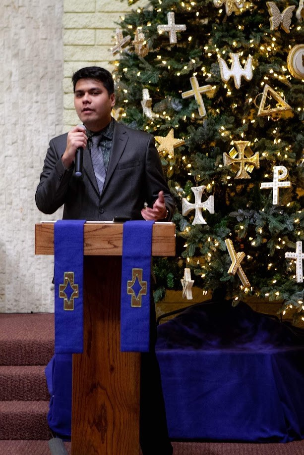 Speaking at the podium beside the Christmas tree at church