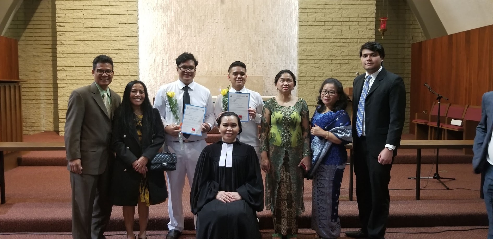Family with the minister after a confirmation service, certificates in hand