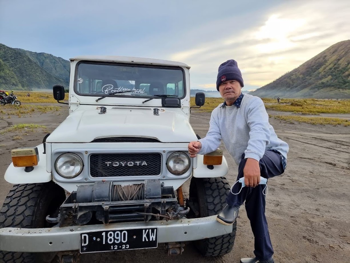 An old Toyota jeep on the sand sea at Mount Bromo at dawn