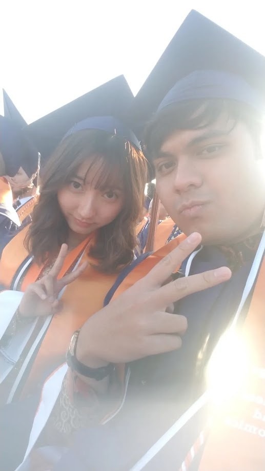 Selfie in cap and gown with a friend at commencement