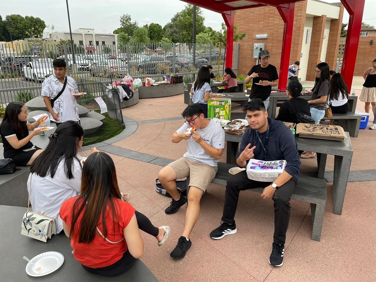 Classmates eating pizza at the outdoor tables on campus