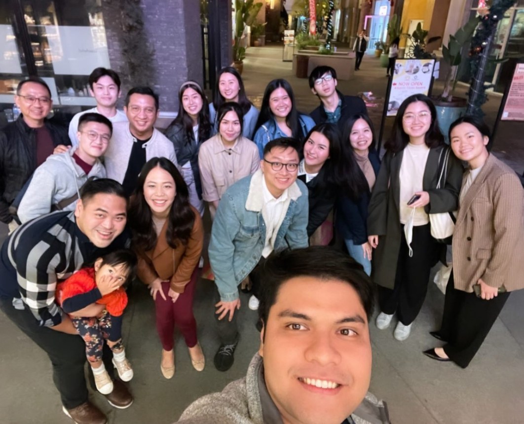 A big group selfie outdoors at night, everyone crowded in together