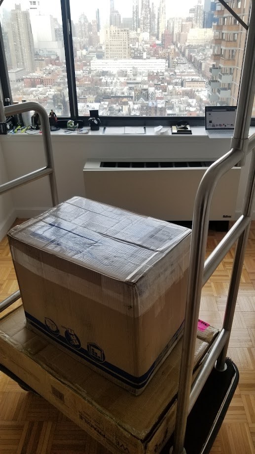 Moving boxes stacked on a trolley in the New York apartment, the city out the window