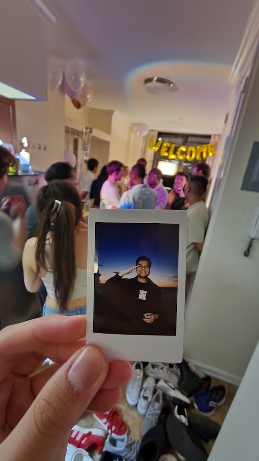 Holding up a polaroid at a housewarming party