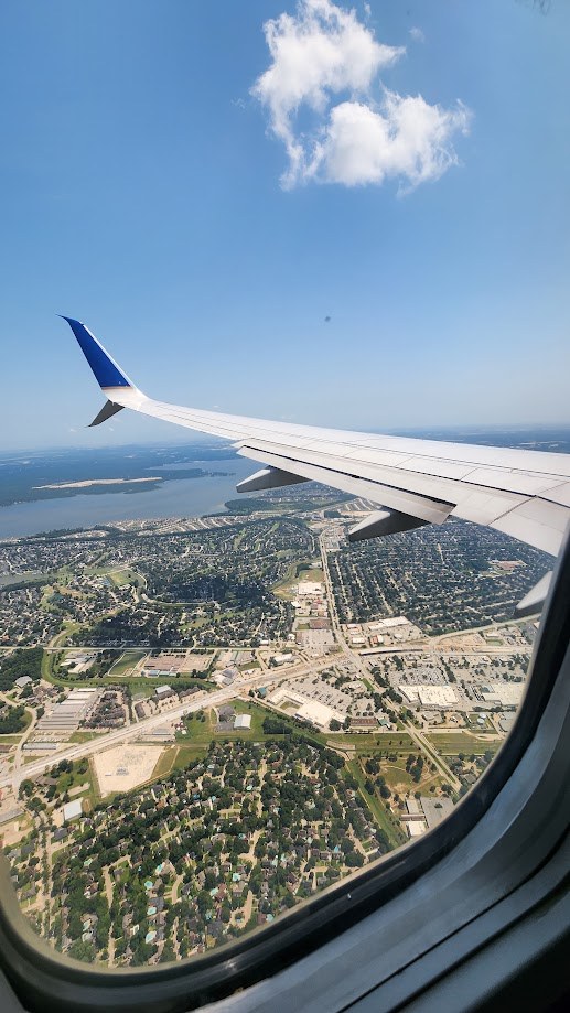 The wing over a green suburb and a lake, shortly after takeoff