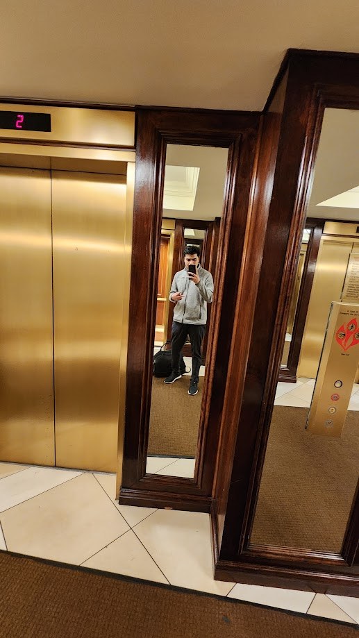 Mirror selfie by the hotel elevators with a duffel bag, heading out early