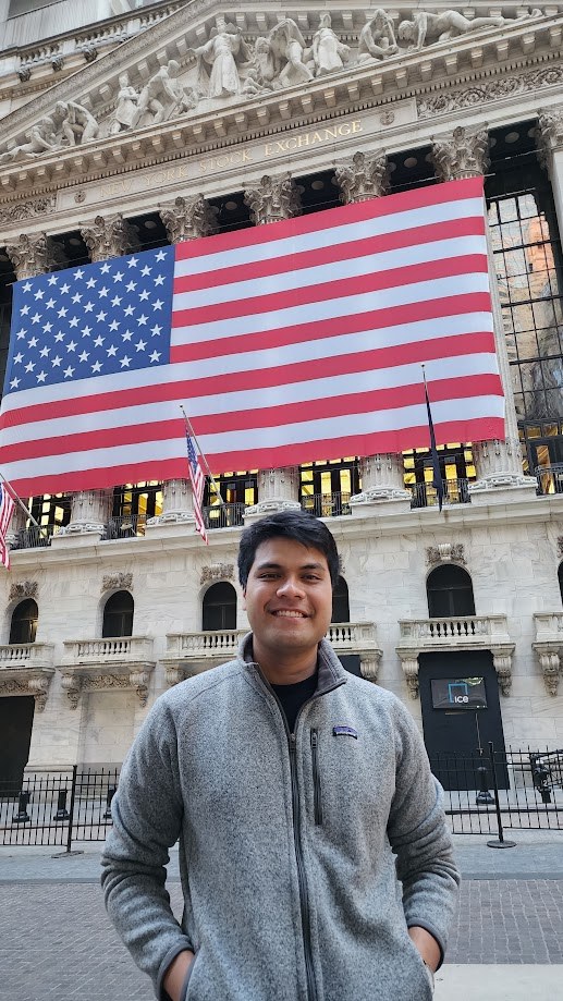 Standing in front of the New York Stock Exchange under the flag