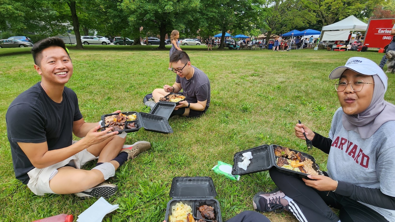 Sitting on the grass with takeout containers at an outdoor festival