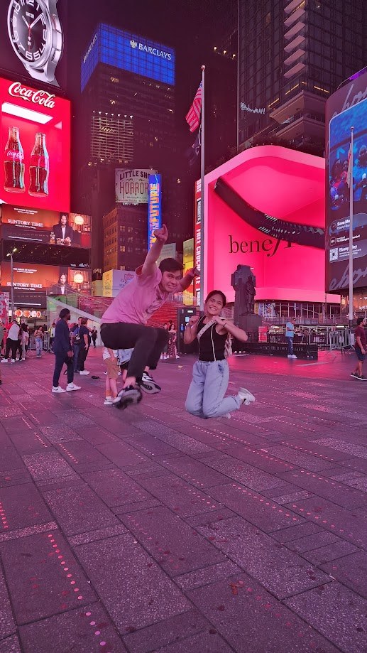 Mid jump in Times Square under the pink billboards