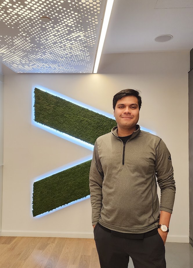 Standing in front of the moss and light Accenture mark in the office lobby