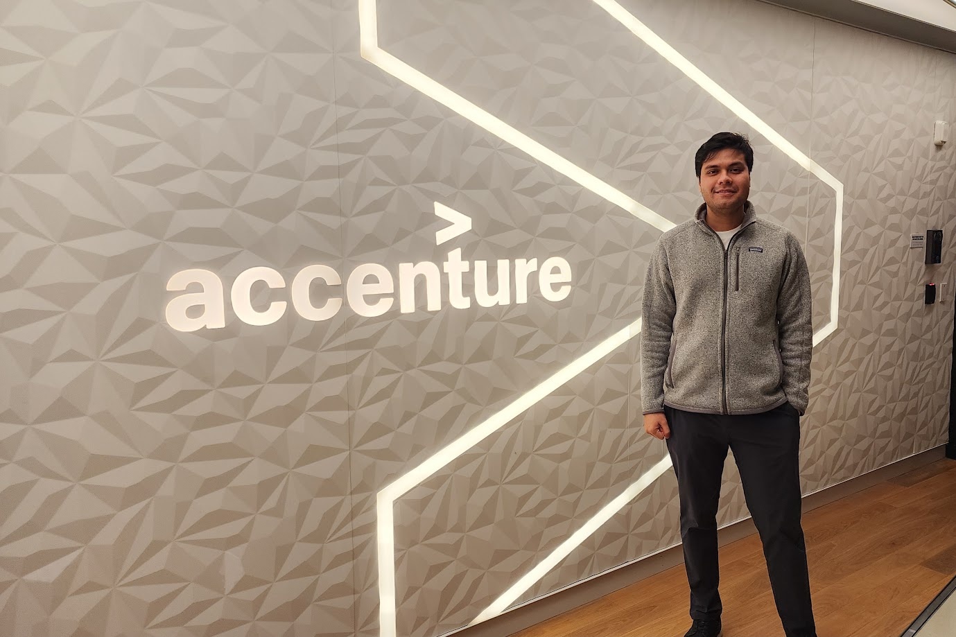 Standing beside the lit Accenture wall in the New York office