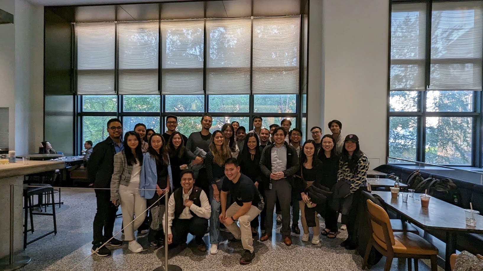 Large team photo in the office lounge in front of the tall windows