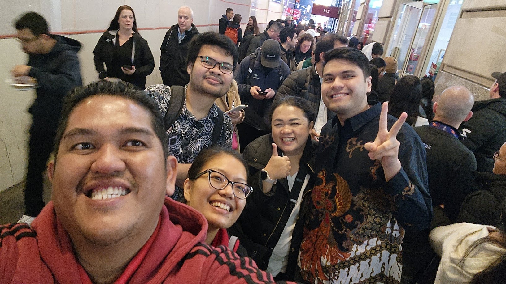 Crowd selfie with friends waiting in a long queue, most of us in batik