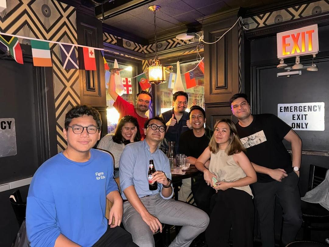Group photo at a pub under a string of national flags