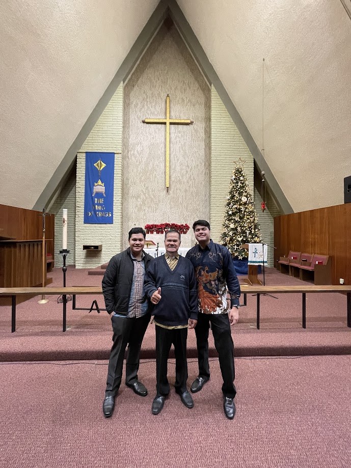 Three of us in front of the cross and the Christmas tree