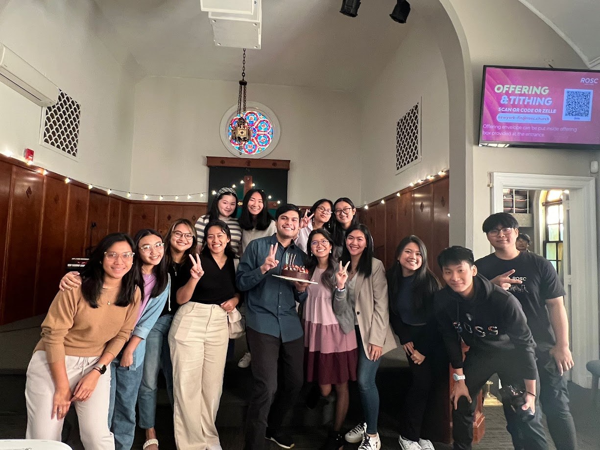 Group photo in the church hall under the rose window, cake in hand
