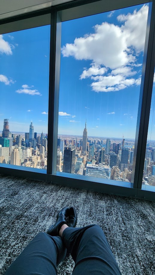 Feet up by the window with the midtown skyline and a bright blue sky