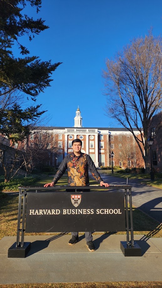 Standing behind the Harvard Business School sign on a clear winter day
