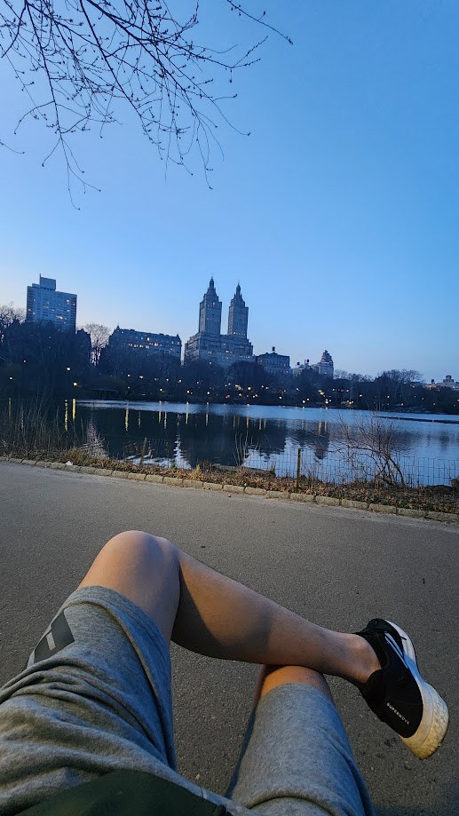Legs stretched out by the lake in Central Park at golden hour
