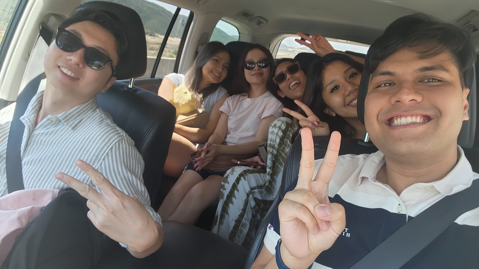 A car full of friends on a road trip, everyone throwing peace signs