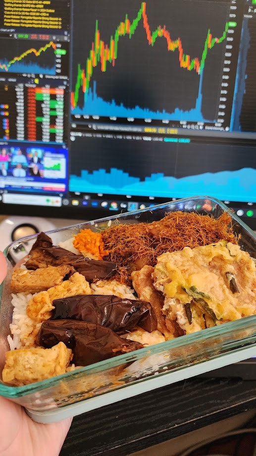 A home cooked lunch box held up in front of the trading screens