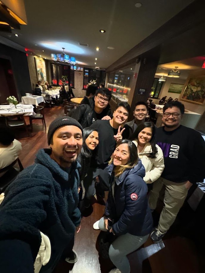 Group selfie in coats and beanies at a restaurant on a cold night