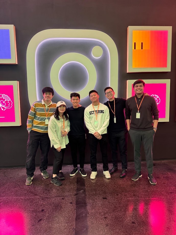 Six of us on lanyards in front of a giant lit Instagram logo